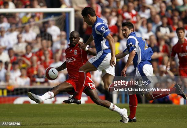 Portsmouth's Dejan Stefanovic and Liverpool's Mohamed Sissoko battle for the ball, as Portsmouth's Richard Hughes looks on.