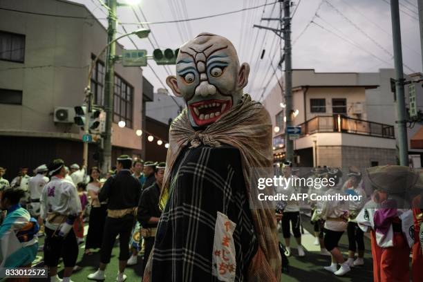 This photo taken on August 16, 2017 shows a dancer disguised as an imaginary monster in Japanese folklore walking on a street at the Ikeda Awa Odori...