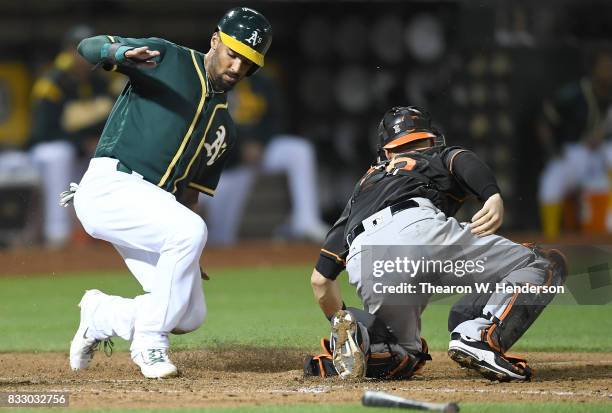 Marcus Semien of the Oakland Athletics scores sliding past catcher Caleb Joseph of the Baltimore Orioles in the bottom of the eighth inning at...