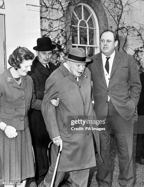 Sir Winston Churchill, the inevitable cigar between his lips, gets an affectionate helping hand from his daughter, Mary, and son-in-law Christopher...