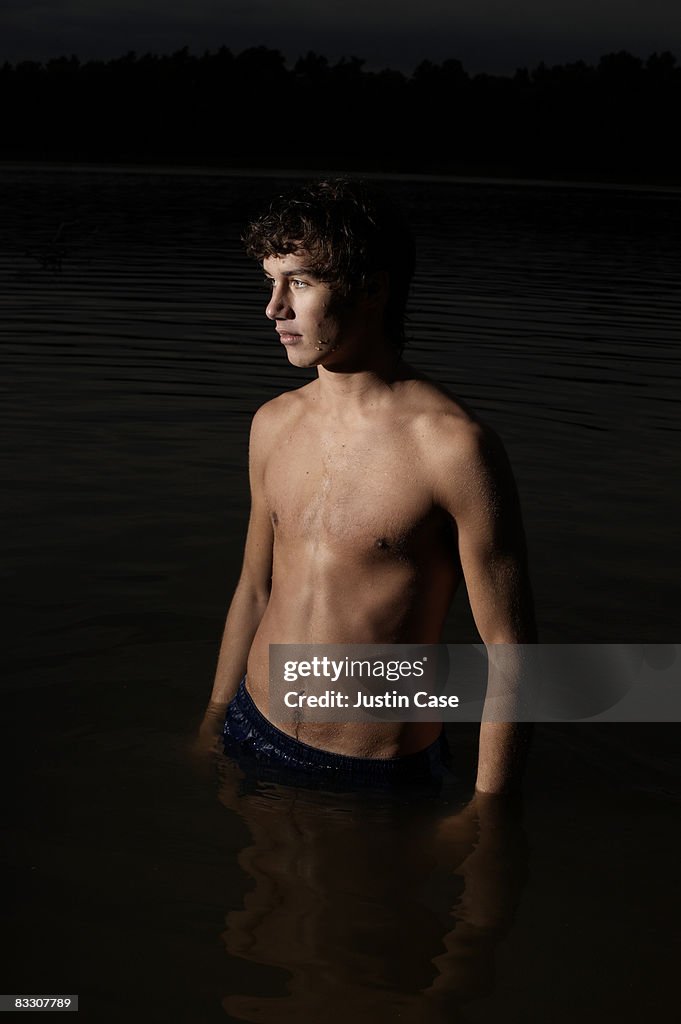 Boy standing waist deep in lake at night