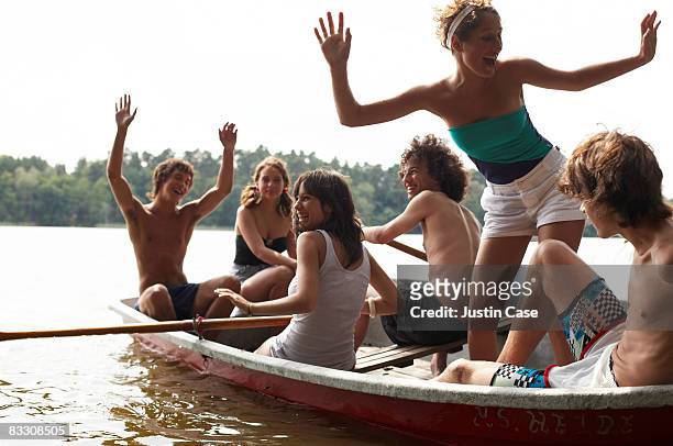 group of friends laughing while sitting in boat - teenagers boat stock-fotos und bilder