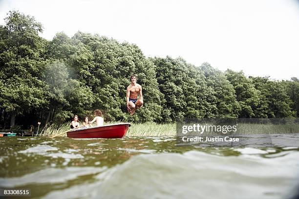 boy jumping from boat into water - andando de chalana - fotografias e filmes do acervo