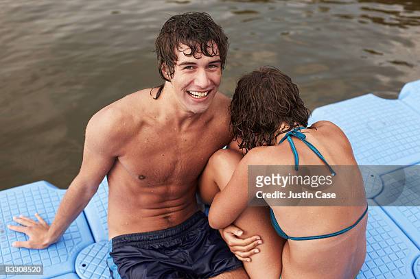 boy and girl sitting on pontoon on lake - young love stock-fotos und bilder