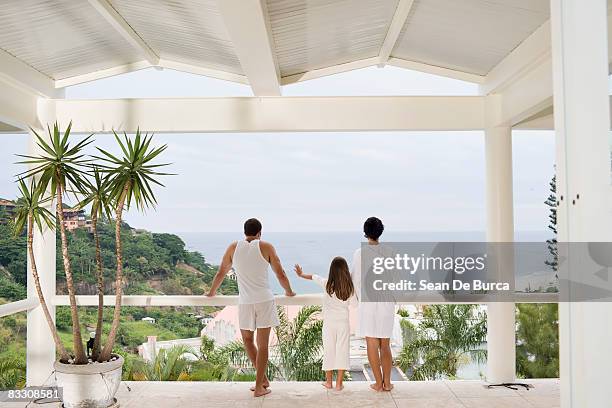 young family looking out to sea - family rear view stock pictures, royalty-free photos & images
