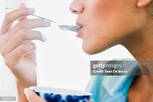 young woman eating yogurt - ätutrustning bildbanksfoton och bilder