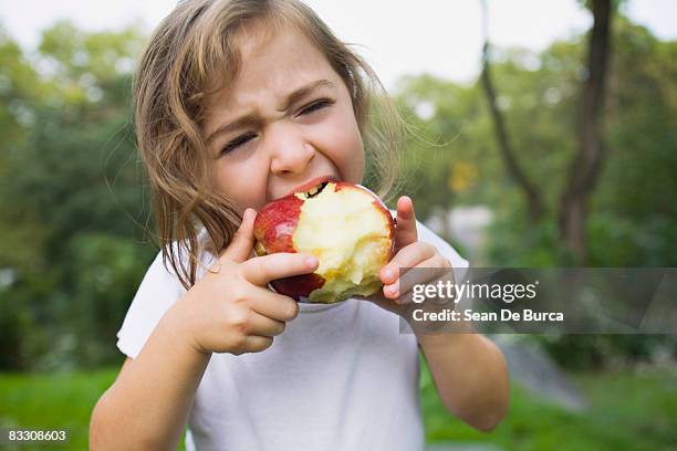 young girl biting apple - child eating a fruit stockfoto's en -beelden