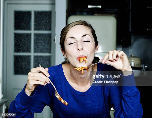 portrait of woman eating spaghetti - indulgence foto e immagini stock