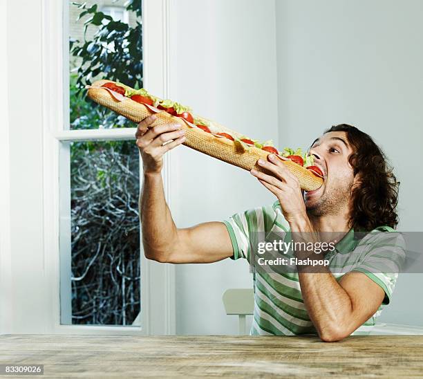 portrait of man eating big baguette - over eating 個照片及圖片檔