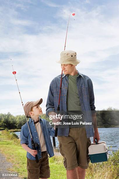 father and son carrying fishing equipment  - fishing pole stock pictures, royalty-free photos & images