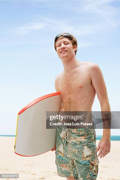 young man with boogie board - bermuda shorts stock pictures, royalty-free photos & images