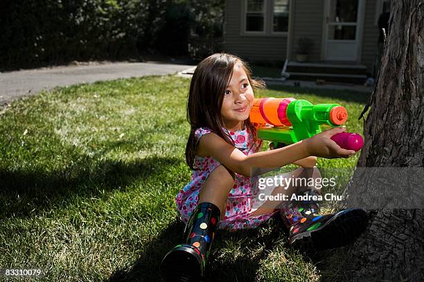 young girl takes aim with water gun in backyard. - water pistol stock pictures, royalty-free photos & images