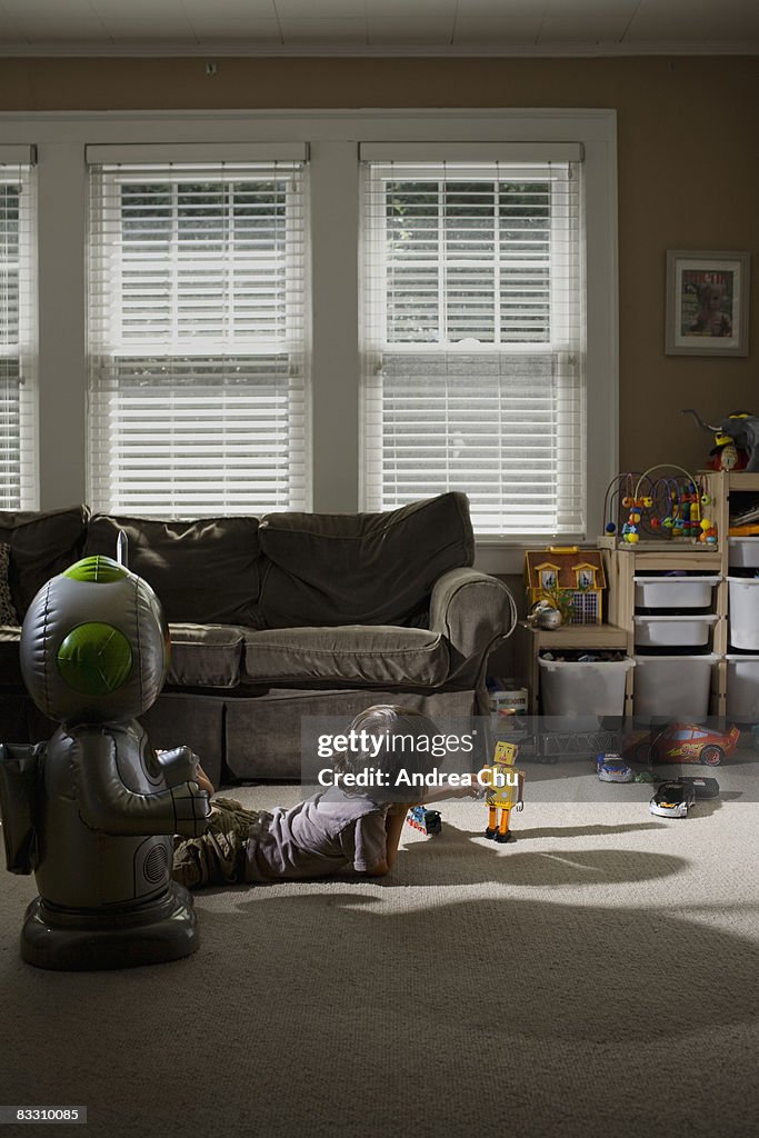 Young boy in living room with toy robot.