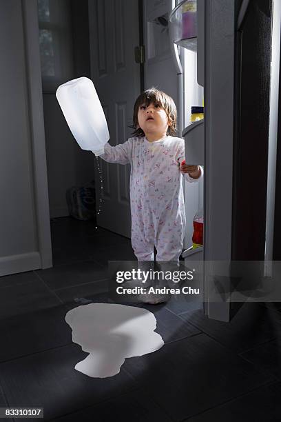 young boy spilling milk on kitchen floor. - milk bottle photos et images de collection