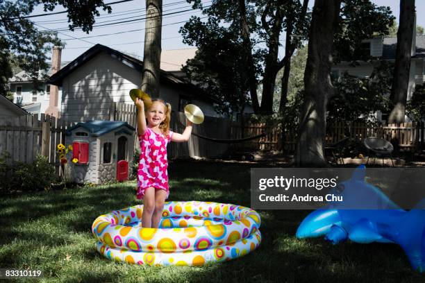 young girl playing with cymbals in a kiddy pool. - cymbal water stock-fotos und bilder