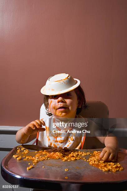 boy having a messy meal in vintage  highchair.   - baby bib stock pictures, royalty-free photos & images