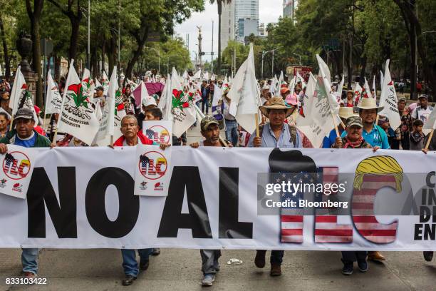 Demonstrators hold a banner and flags during a protest against the North American Free Trade Agreement in Mexico City, Mexico, on Wednesday, Aug. 16,...