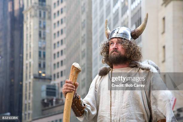 viking looking up at tall buildings in the city. - viking helmet stock-fotos und bilder