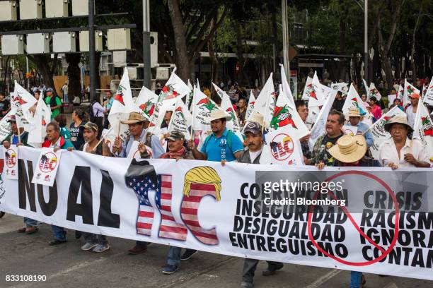Demonstrators hold a banner and flags during a protest against the North American Free Trade Agreement in Mexico City, Mexico, on Wednesday, Aug. 16,...