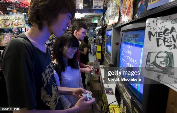 Visitors plays a video game on the Nintendo Co. Super Nintendo Entertainment System console at the Super Potato video game store in the Akihabara...