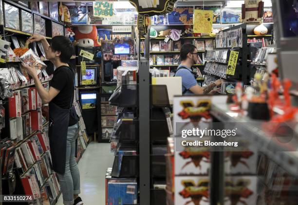 An employee, left, arranges video games as a customer shops at the Super Potato video game store in the Akihabara district of Tokyo, Japan, on...