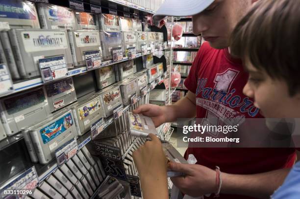 French tourists shop for video game titles for the Nintendo Co. Super Nintendo Entertainment System console at the Super Potato video game store in...