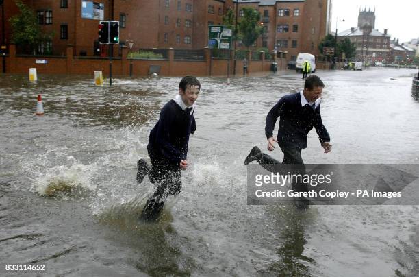 School children run through flood waters after the banks of the River Aire in Leeds city centre are broken by heavy rain fall.