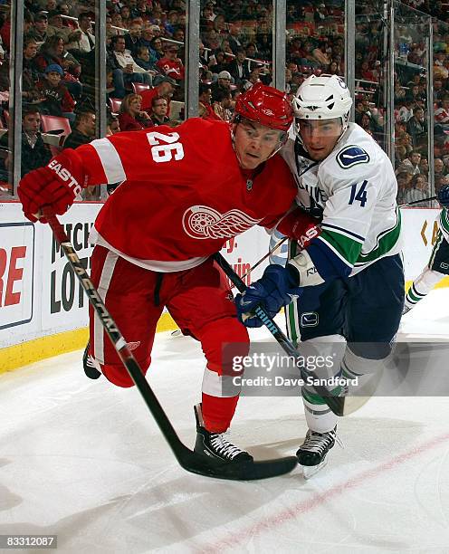 Alex Burrows of the Vancouver Canucks battles for position with Jiri Hudler of the Detroit Red Wings during their NHL game at Joe Louis Arena October...