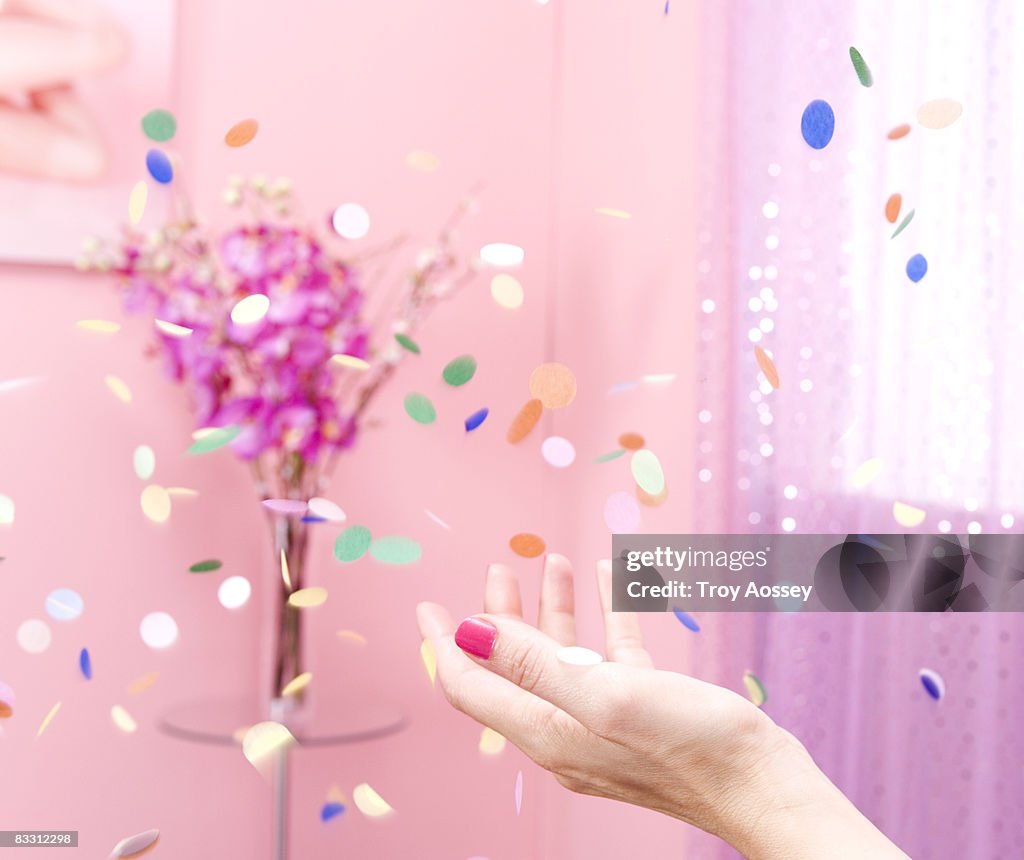 Hand throwing confetti in pink room