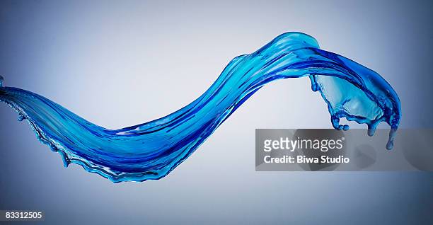 blue splash water on blue back - liquefatto foto e immagini stock