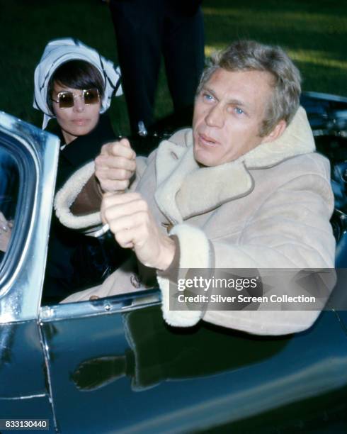 American actor Steve McQueen with his wife, Filipino-american actress Neile Adams in a convertible sport car, circa 1965.