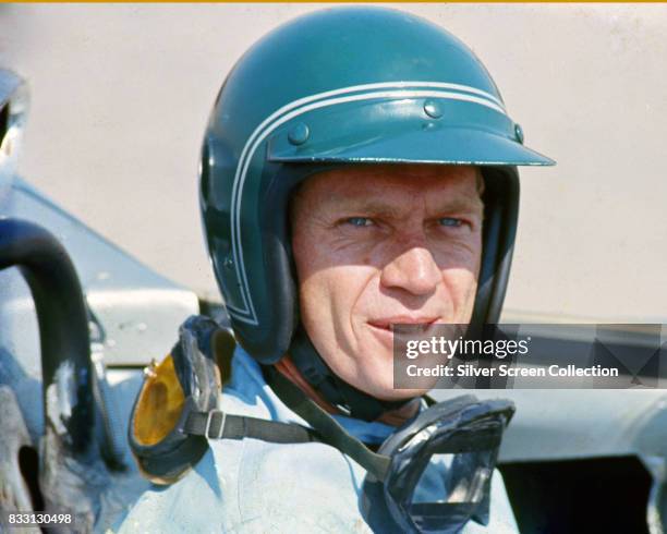 American actor Steve McQueen in Firestone racing driver suit sitting inside a Lola T70 SL70/14 car, at Riverside Raceway in Riverside, California,...