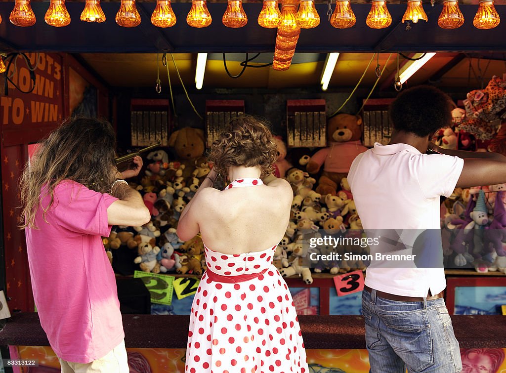 Three people at funfair rifle range