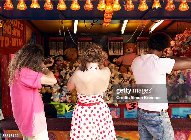 three people at funfair rifle range - fairground stall stock pictures, royalty-free photos & images