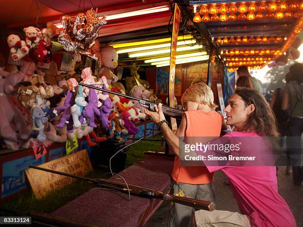 father and son at funfair rifle range - fairground stall stock pictures, royalty-free photos & images