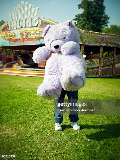 woman with huge teddy bear at funfair - stofftier stock-fotos und bilder