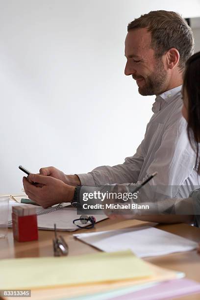 receiveing texto during a meeting - texto stockfoto's en -beelden