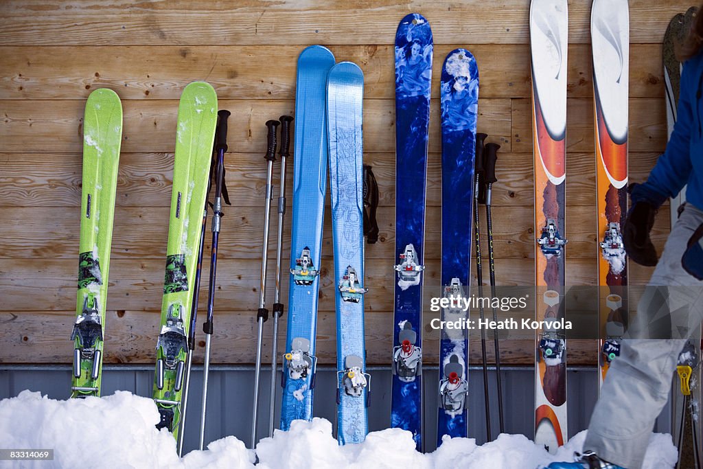 Colorful array of skis lined up against cabin.