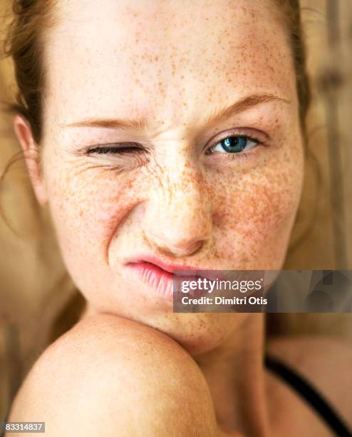 freckle faced woman winking, close-up - augenzwinkern stock-fotos und bilder