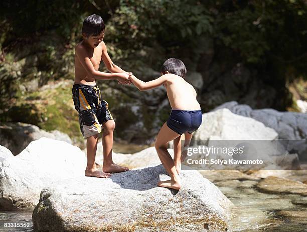 japanese boy lifting up his friend from river - rising damp stock pictures, royalty-free photos & images
