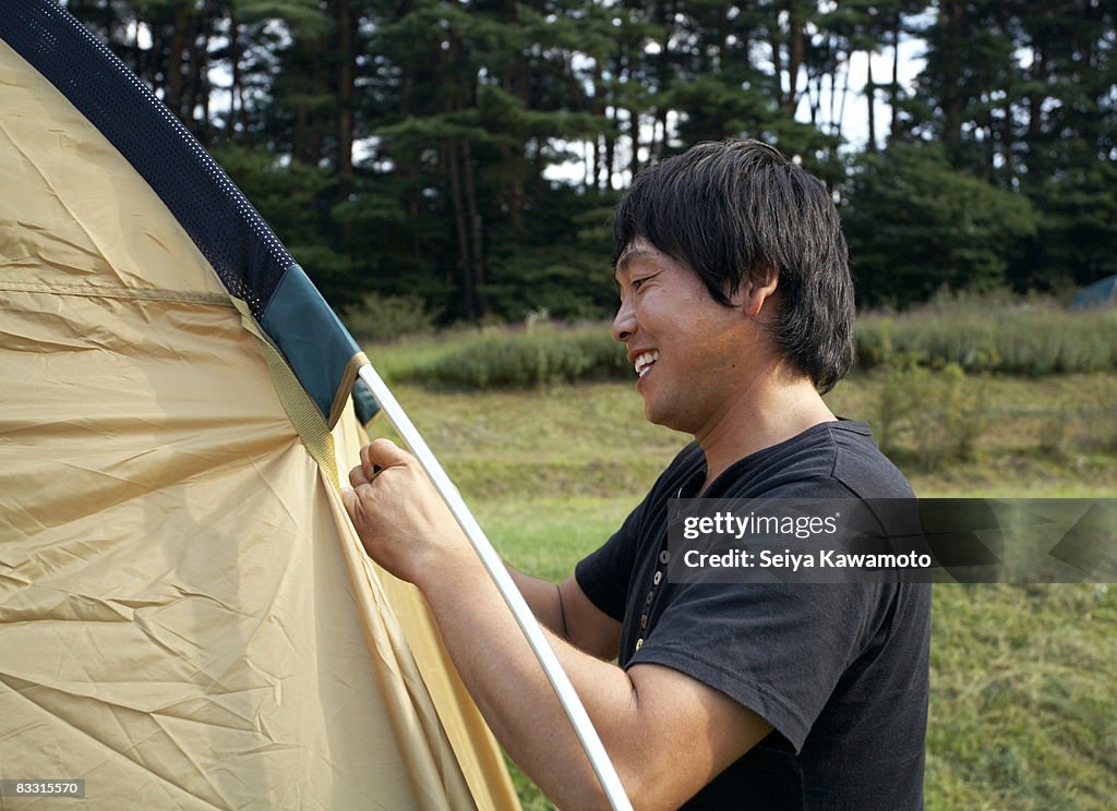 Japanese homem preparando um acampamento para barraca