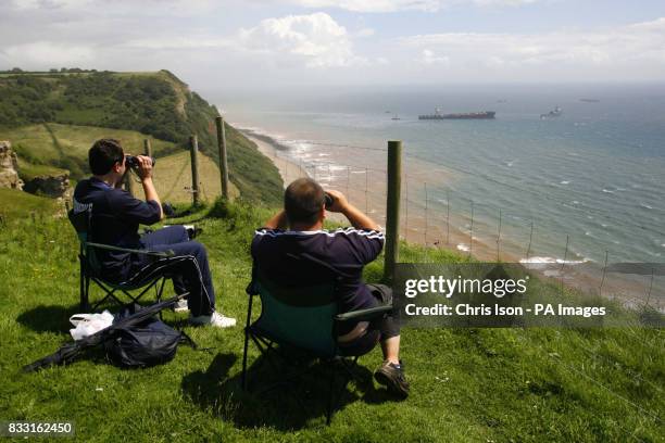 Two men sit on the cliff top waiting to see explosive devices blow apart the deck of the stricken container ship MSC Napoli off the South Devon coast...