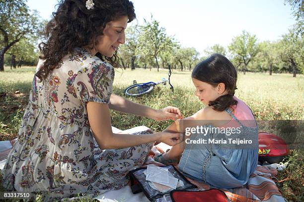 mother putting plaster on daughters elbow - bandage stock pictures, royalty-free photos & images