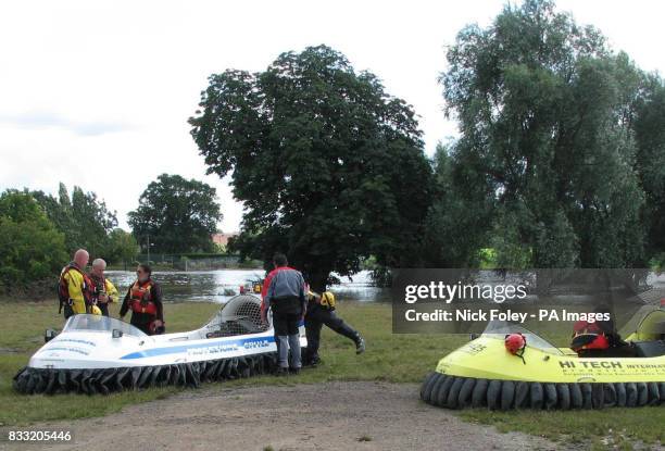 Three Italian volunteers from Protezione Nazionale stand next to their hovercraft in Tewkesbury where a body was discovered in a submerged park.