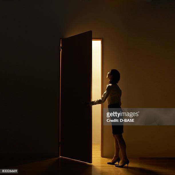 business woman opening  door standing in light - portal fotografías e imágenes de stock