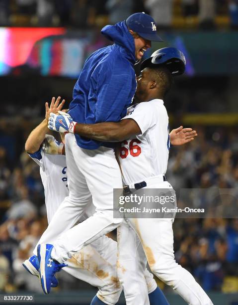 Clayton Kershaw of the Los Angeles Dodgers leaps into the arms of Yasiel Puig of the Los Angeles Dodgers after Puig hit a walk off three-run home run...