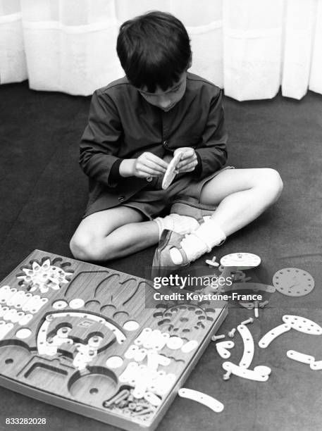 Enfant jouant à un jeu de construction mécanique, en France.