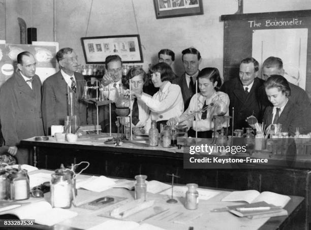 Des pères regardent leurs filles utilisant l'équipement du laboratoire lors d'une démonstration d'un cours de chimie, le 25 octobre 1932, à l'École...
