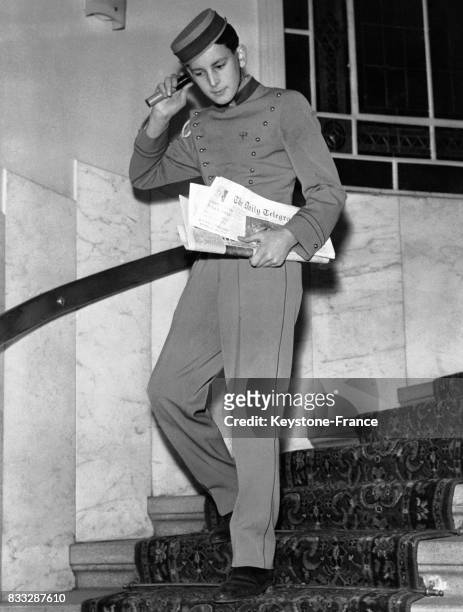 Jeune apprenti groom service en uniforme descendant les escaliers d'un hôtel avec sous le bras des journaux, le 31 janvier 1959, à Vienne, Autriche.