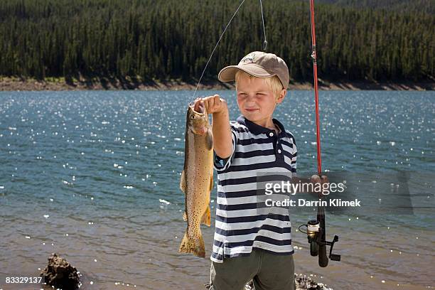 boy holding up fish he caught - catching fish stock pictures, royalty-free photos & images